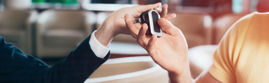 panoramic close-up of both man and woman, hands holding car keys